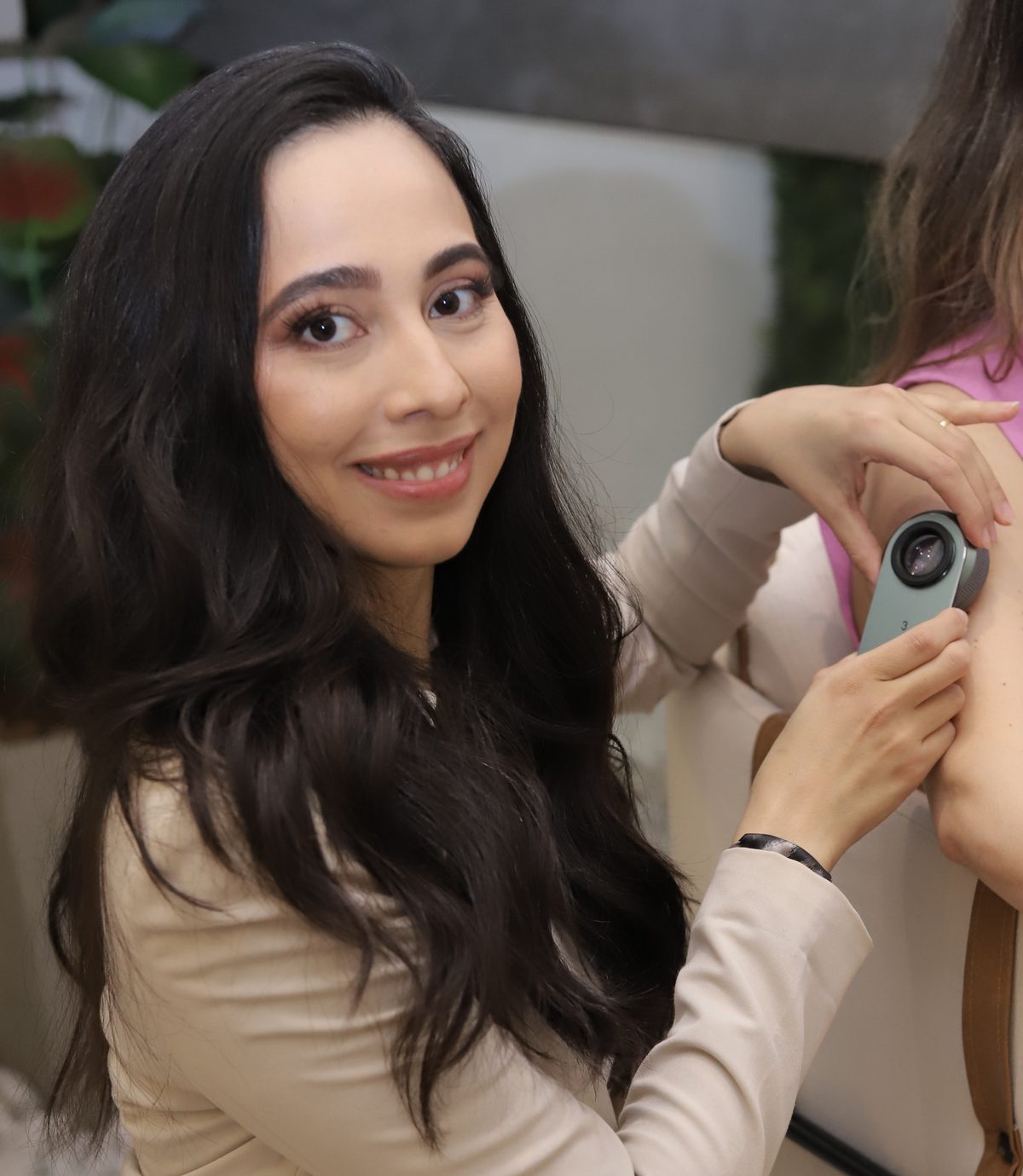 Dra. Stephanie Mansan examinando uma pinta no braço de uma paciente com o dermatoscópio